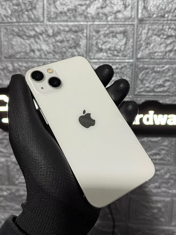 iPhone 13 branco segurado com luva preta na loja