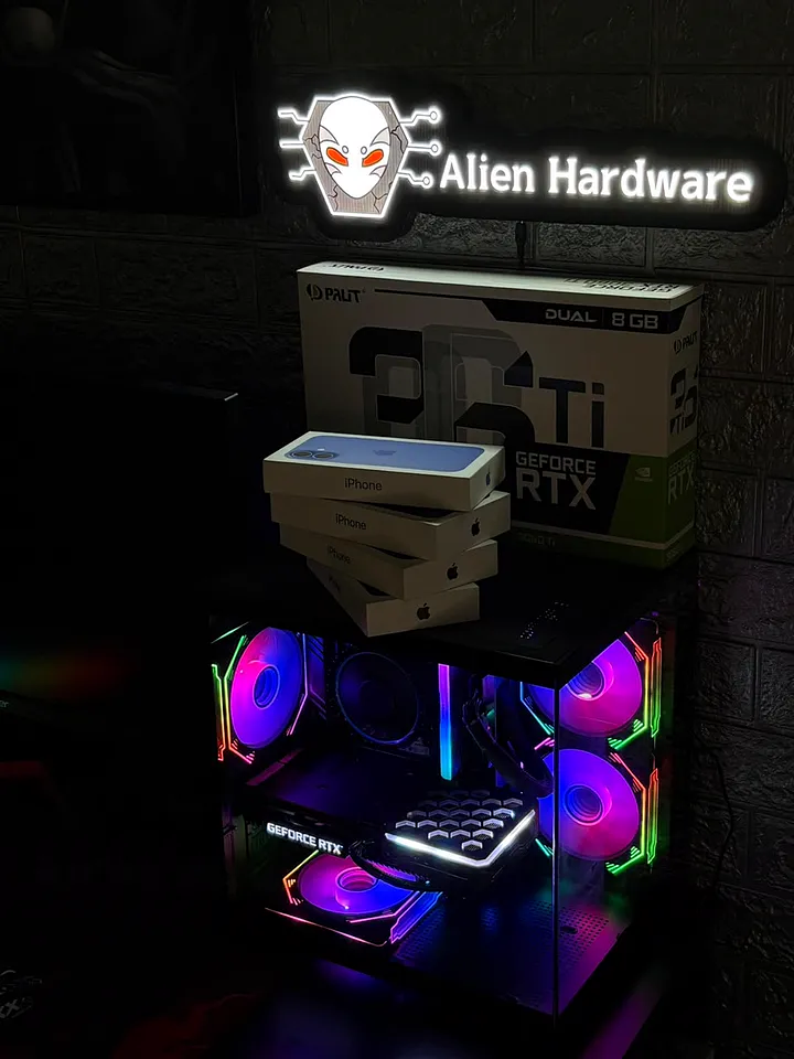 PC gamer em gabinete aquário com fans RGB rosa e roxo, com a caixa de uma RTX 3060 Ti e caixas de iPhone em cima